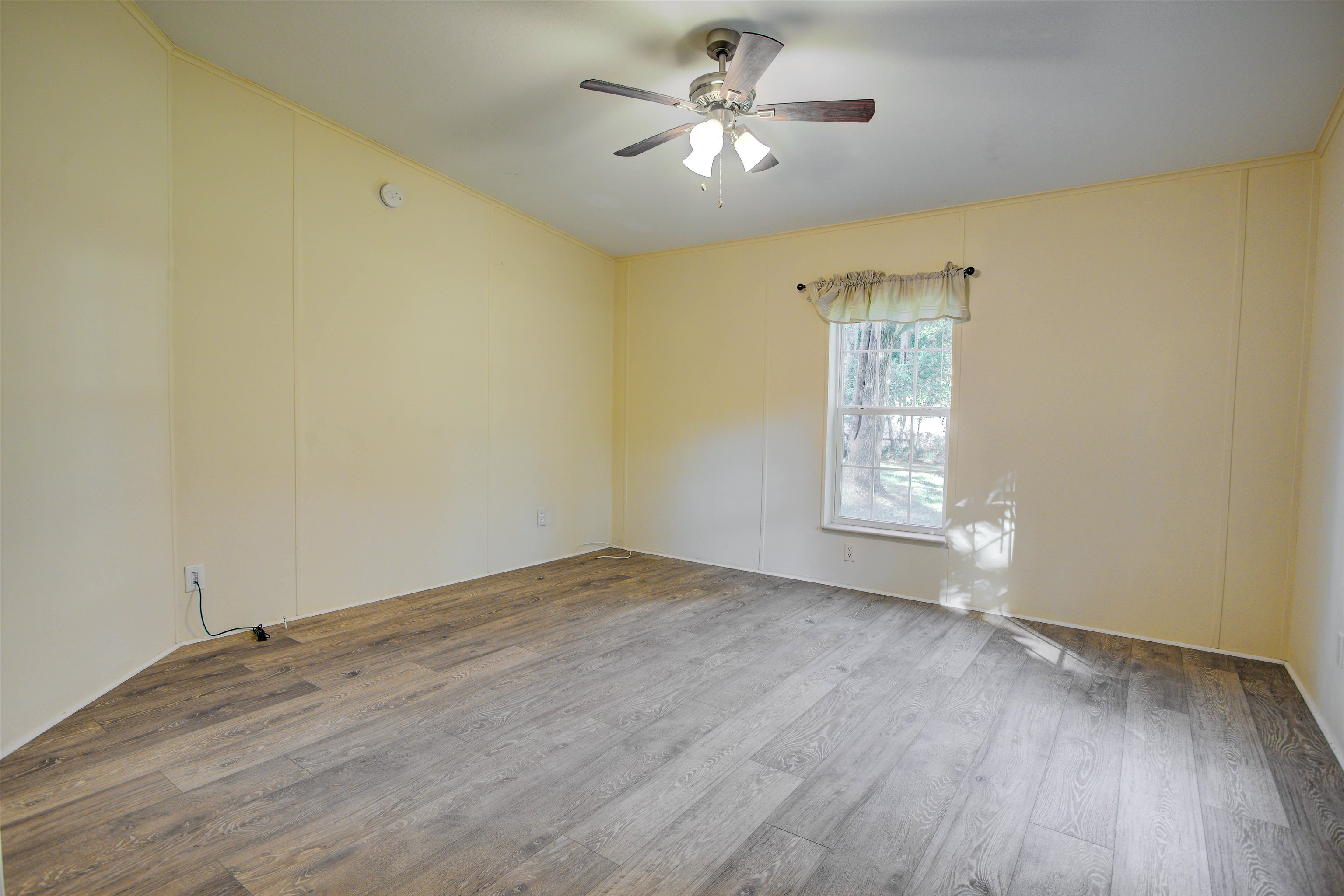 501 Hayley Road St. Augustine, FL 32086 - Photo 26 of 49 Empty room with a decorative wall, wood finished floors, and ceiling fan