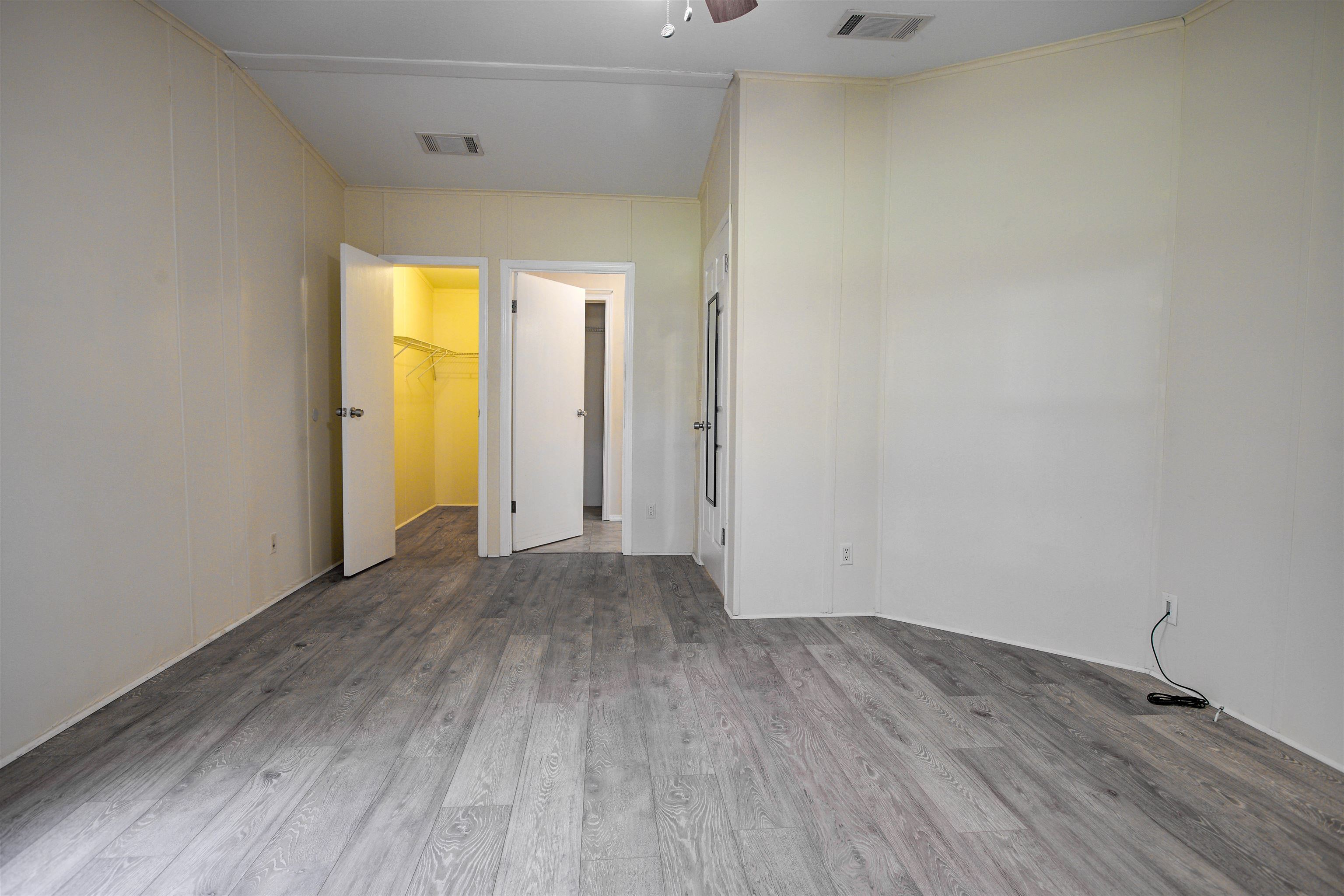 501 Hayley Road St. Augustine, FL 32086 - Photo 29 of 49 Unfurnished bedroom featuring light wood-style floors, a spacious closet, a ceiling fan, and a decorative wall