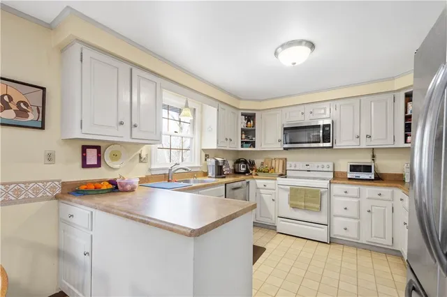 a kitchen with stainless steel appliances a sink a stove a refrigerator cabinets and a window