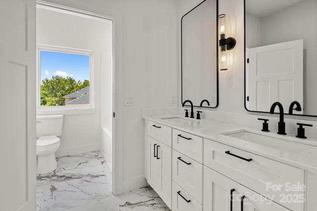 a bathroom with double vanity sink two mirror and window