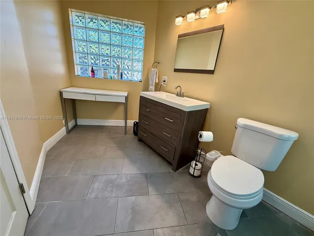 a bathroom with a toilet a sink a mirror and a window