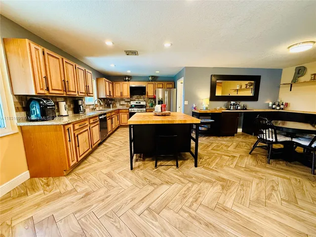 a view of a kitchen with kitchen island granite countertop wooden floors and a sink