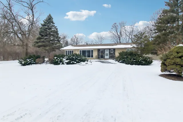 a front view of a house with a yard covered in snow