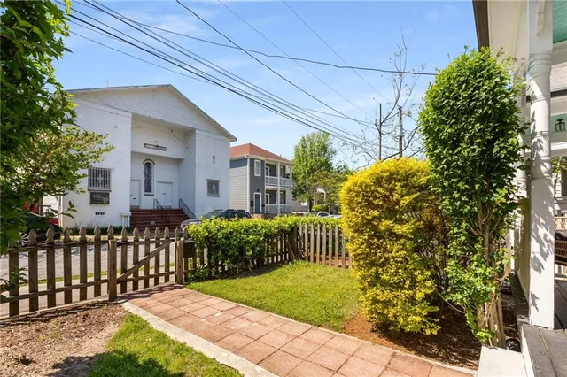 a view of a house with brick walls plants and large tree