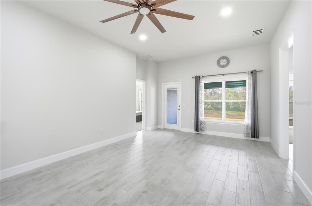 12945 Ogden Glade Road Dade City, FL 33525 - Photo 12 of 26 an empty room with wooden floor fan and windows