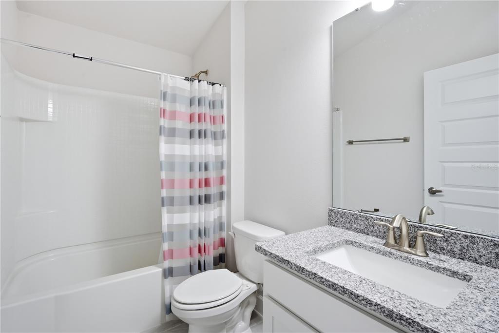 12945 Ogden Glade Road Dade City, FL 33525 - Photo 15 of 26 a bathroom with a granite countertop sink a toilet and shower