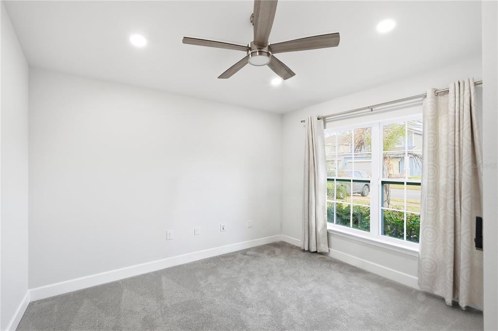 12945 Ogden Glade Road Dade City, FL 33525 - Photo 5 of 26 an empty room with a ceiling fan and windows