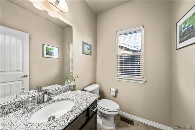 a bathroom with a granite countertop toilet a sink and a mirror