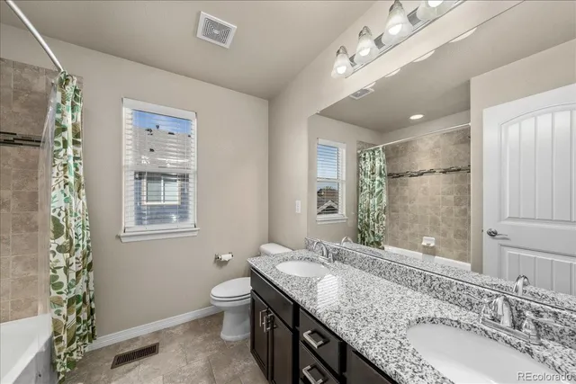 a bathroom with a granite countertop double vanity sink mirror and shower
