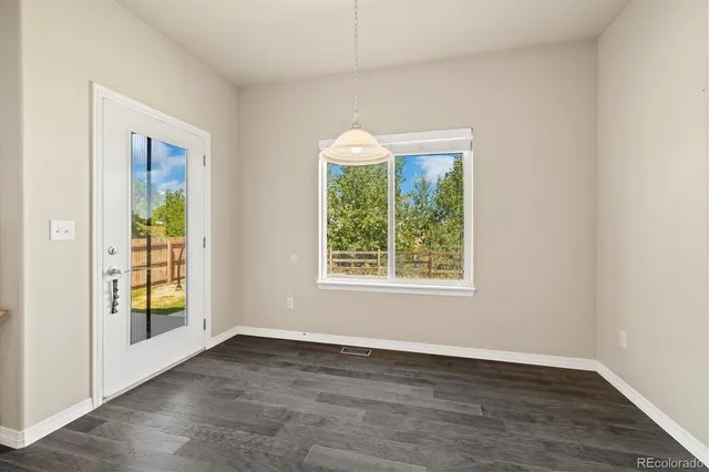 an empty room with wooden floor a exposed radiator and a window