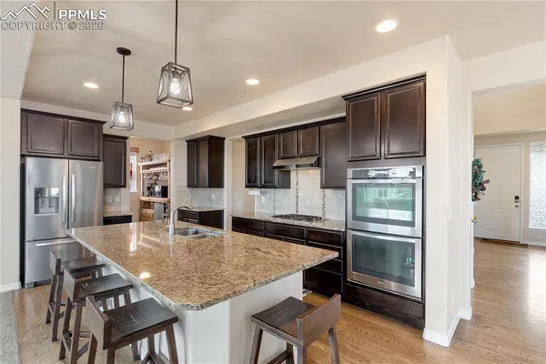 a kitchen with stainless steel appliances granite countertop a sink refrigerator and cabinets