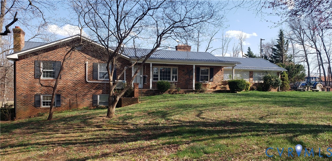a view of a house with a yard fire pit and a large tree