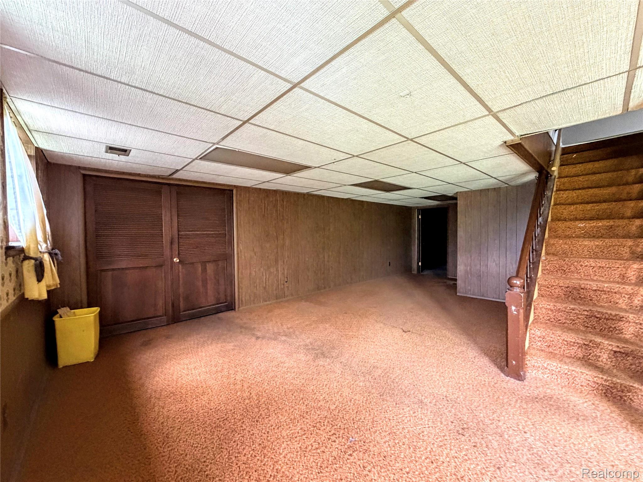8079 Farley Road Pinckney, MI 48169 - Photo 29 of 43 Finished below grade area featuring light colored carpet, wood walls, and a paneled ceiling