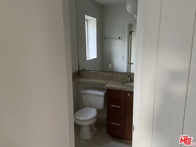 a bathroom with a granite countertop toilet and a sink