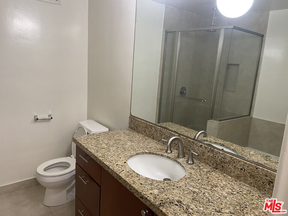 10655 Wilshire Boulevard, Unit 303 Los Angeles, CA 90024 - Photo 18 of 27 a bathroom with a granite countertop sink a mirror and a toilet