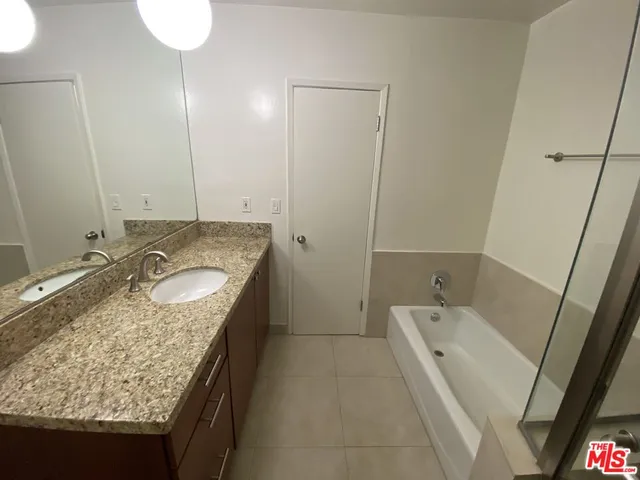 a bathroom with a granite countertop sink a mirror and shower