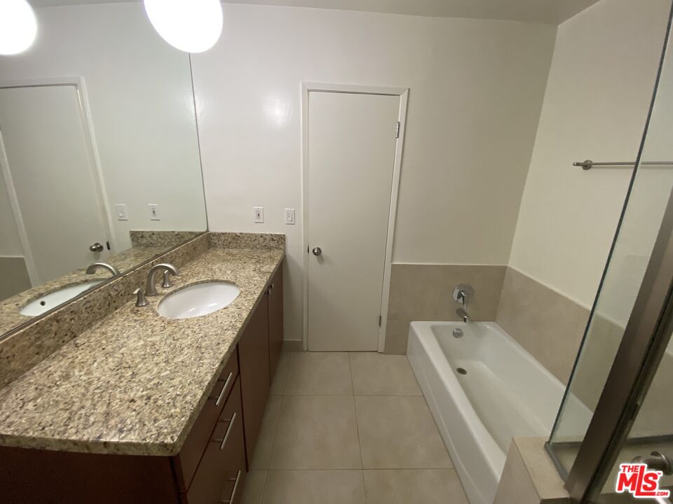10655 Wilshire Boulevard, Unit 303 Los Angeles, CA 90024 - Photo 20 of 27 a bathroom with a granite countertop sink and mirror with bathtub