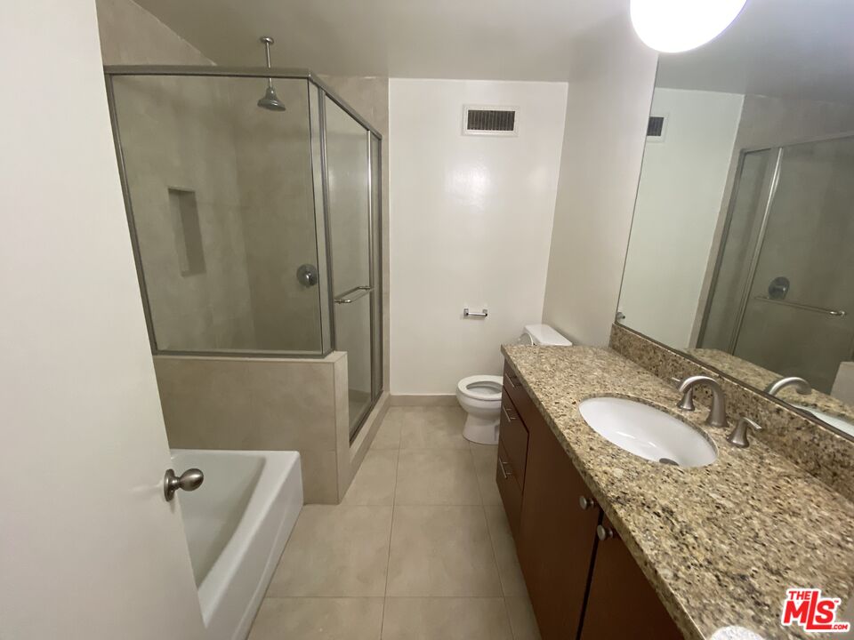 10655 Wilshire Boulevard, Unit 303 Los Angeles, CA 90024 - Photo 21 of 27 a bathroom with a granite countertop sink a mirror and shower
