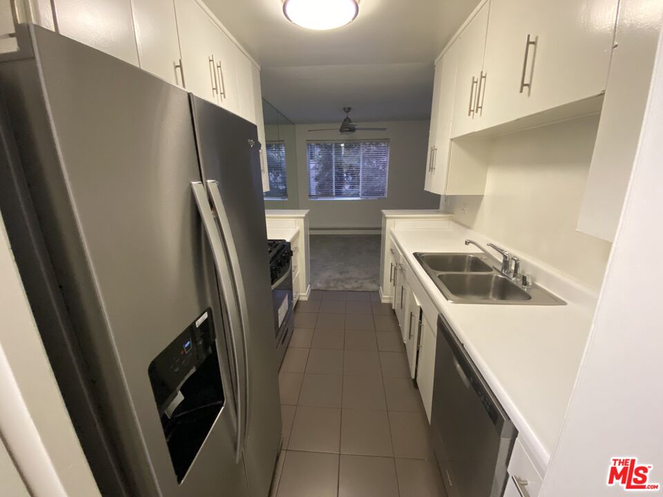 10655 Wilshire Boulevard, Unit 303 Los Angeles, CA 90024 - Photo 24 of 27 a kitchen with stainless steel appliances a refrigerator a sink a stove and white cabinets