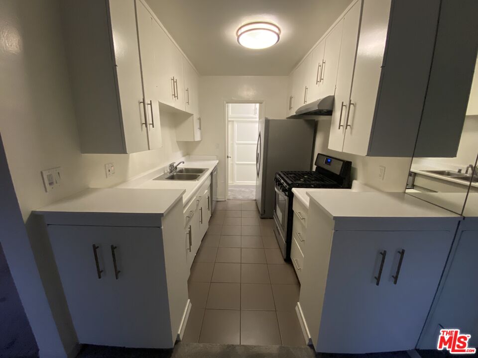 10655 Wilshire Boulevard, Unit 303 Los Angeles, CA 90024 - Photo 25 of 27 a kitchen with a sink a refrigerator and cabinets