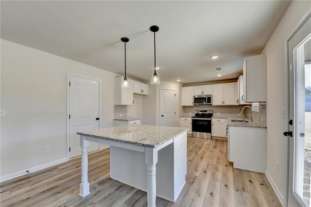 646 Rodeo Drive Auburn, GA 30011 - Photo 14 of 26 a kitchen with a center island white cabinets and stainless steel appliances