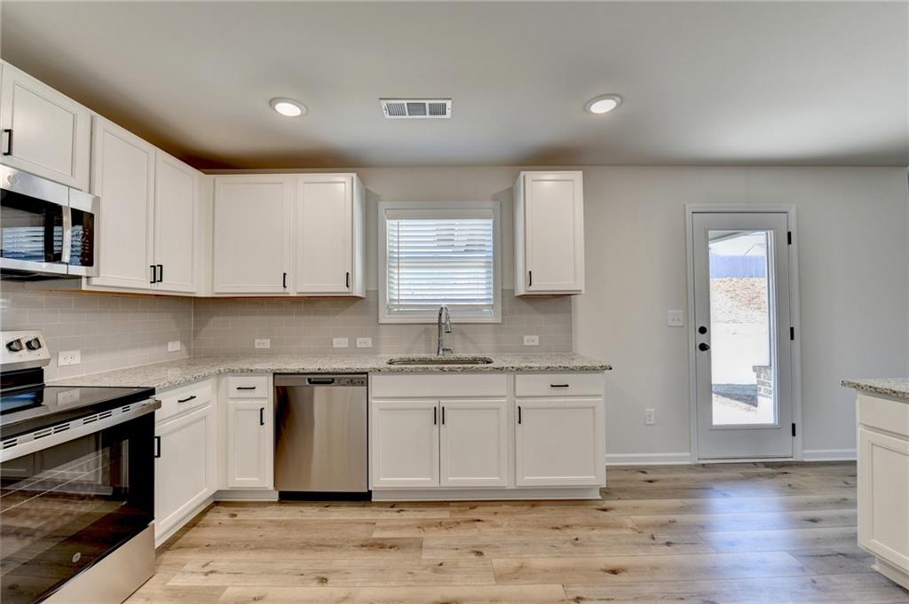 646 Rodeo Drive Auburn, GA 30011 - Photo 16 of 26 a kitchen with stainless steel appliances granite countertop a stove a sink and a microwave