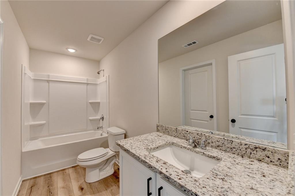 646 Rodeo Drive Auburn, GA 30011 - Photo 18 of 26 a bathroom with a granite countertop sink a toilet and shower