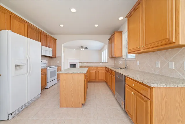 a large kitchen with stainless steel appliances granite countertop a refrigerator a sink dishwasher a stove and a microwave oven with white cabinets