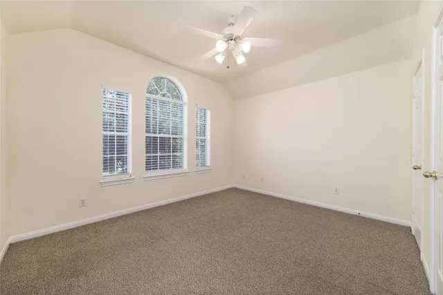 an empty room with windows and ceiling fan