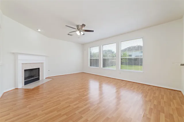 a view of empty room with wooden floor and fan