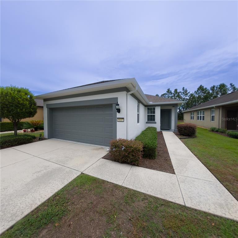 9117 Southwest 70th Loop Ocala, FL 34481 - Photo 2 of 24 a front view of a house with a yard and garage