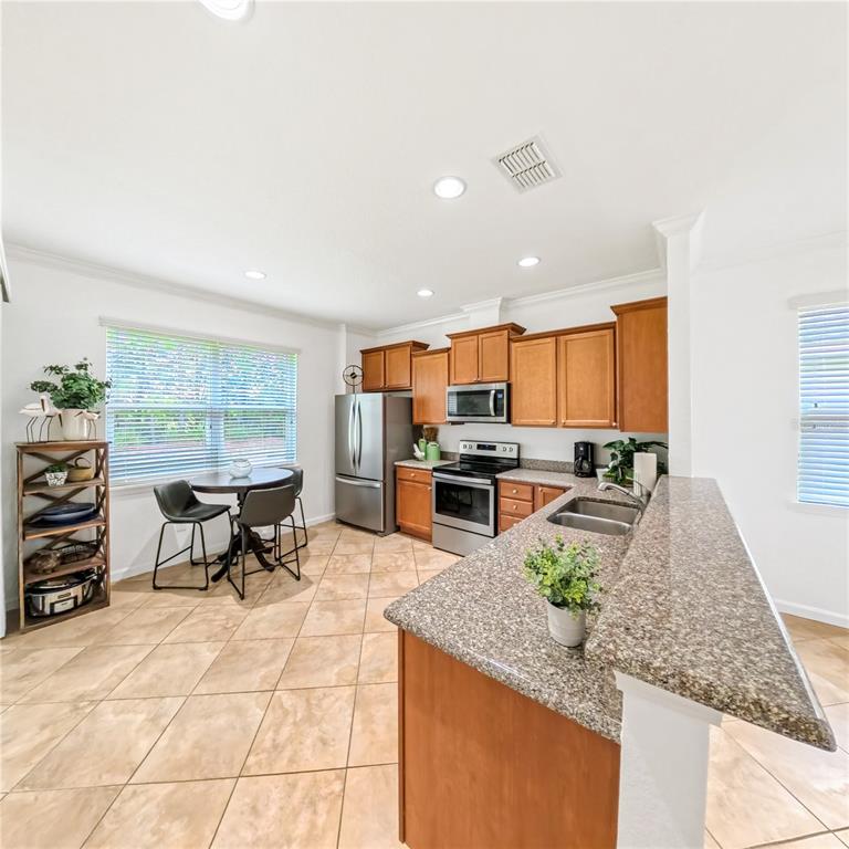 9117 Southwest 70th Loop Ocala, FL 34481 - Photo 10 of 24 a kitchen with stainless steel appliances kitchen island granite countertop a table chairs and a refrigerator