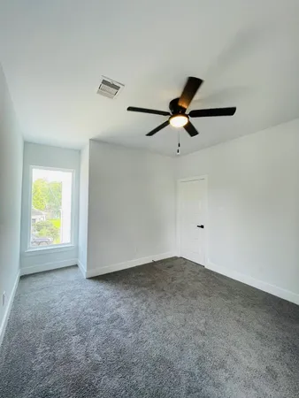 an empty room with windows and a ceiling fan