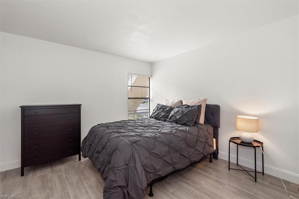 5665 Trailwinds Drive, Unit 616 Fort Myers, FL 33907 - Photo 17 of 29 a bedroom with a bed and a lamp on dresser