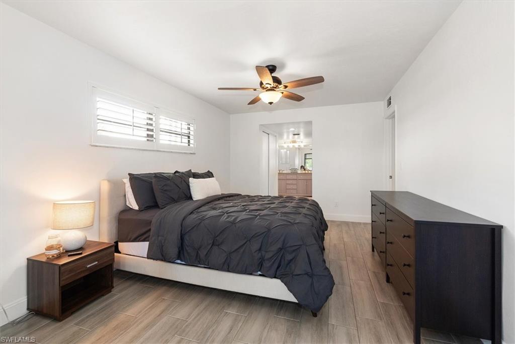 5665 Trailwinds Drive, Unit 616 Fort Myers, FL 33907 - Photo 21 of 29 a spacious bedroom with a bed and a lamp on the dresser
