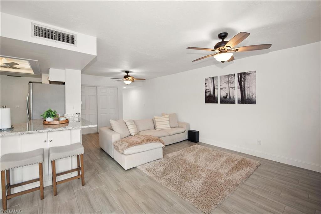 5665 Trailwinds Drive, Unit 616 Fort Myers, FL 33907 - Photo 7 of 29 a living room with furniture and a wooden floor