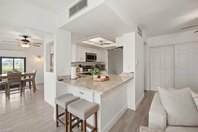 a kitchen with stainless steel appliances granite countertop white cabinets a sink and a stove