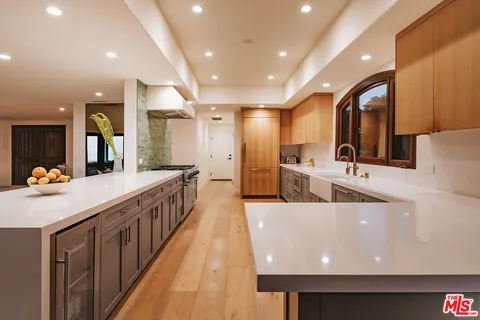 a large kitchen with stainless steel appliances a large counter top a stove and a sink