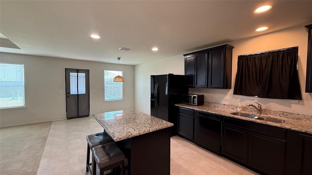 3312 Biggs Avenue Aubrey, TX 76227 - Photo 5 of 19 a kitchen with granite countertop cabinets sink and refrigerator