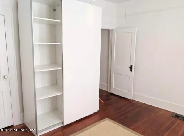 a view of an empty walk in closet with wooden floor