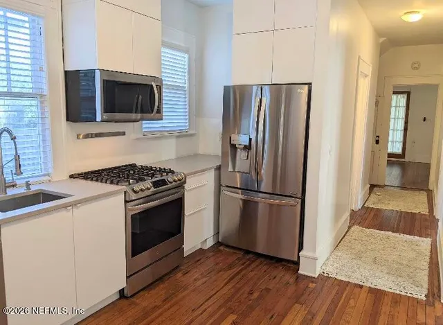 a kitchen with a refrigerator stove and wooden floor