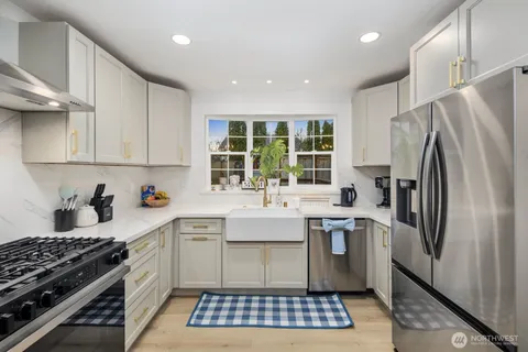 a kitchen with stainless steel appliances a sink a stove a refrigerator cabinets and a window