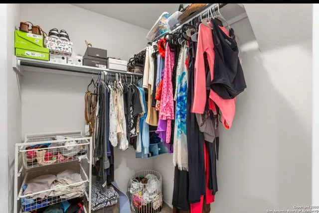 a view of walk in closet with clothes and shoes