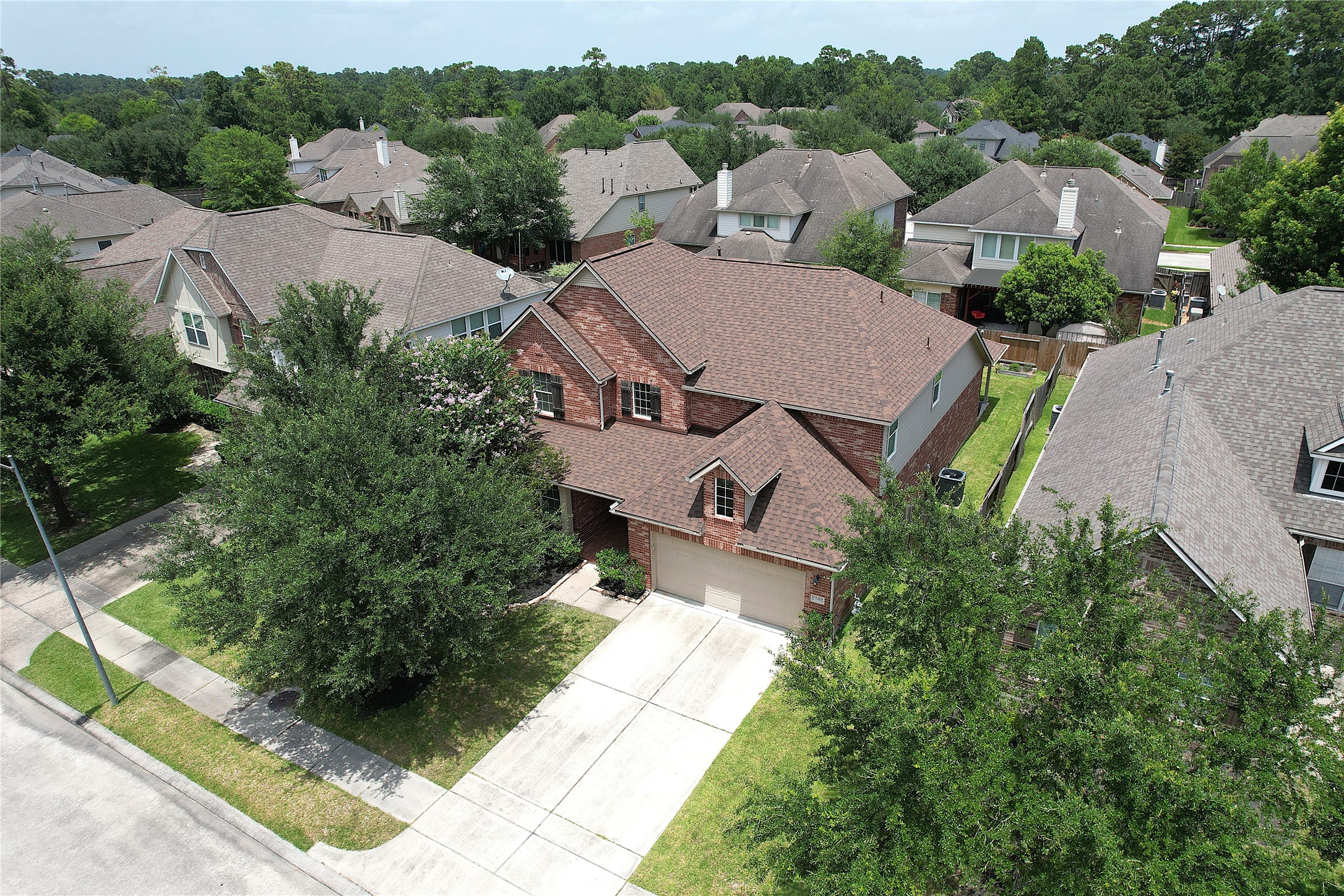 17402 Rainer Valley Lane Humble, TX 77346 - Photo 30 of 33 This photo showcases a two-story, red-brick house with a well-maintained front lawn and a two-car driveway. It's located in a suburban neighborhood with tree-lined streets and similar style homes, offering a peaceful and attractive setting.