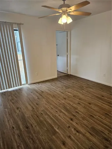 an empty room with wooden floor fan and windows