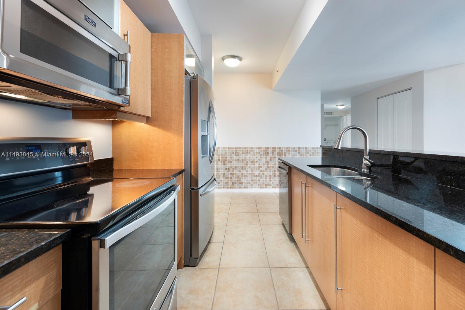 7355 Southwest 89th Street, Unit 510N Miami, FL 33156 - Photo 11 of 52 a kitchen with granite countertop stainless steel appliances and wooden cabinets