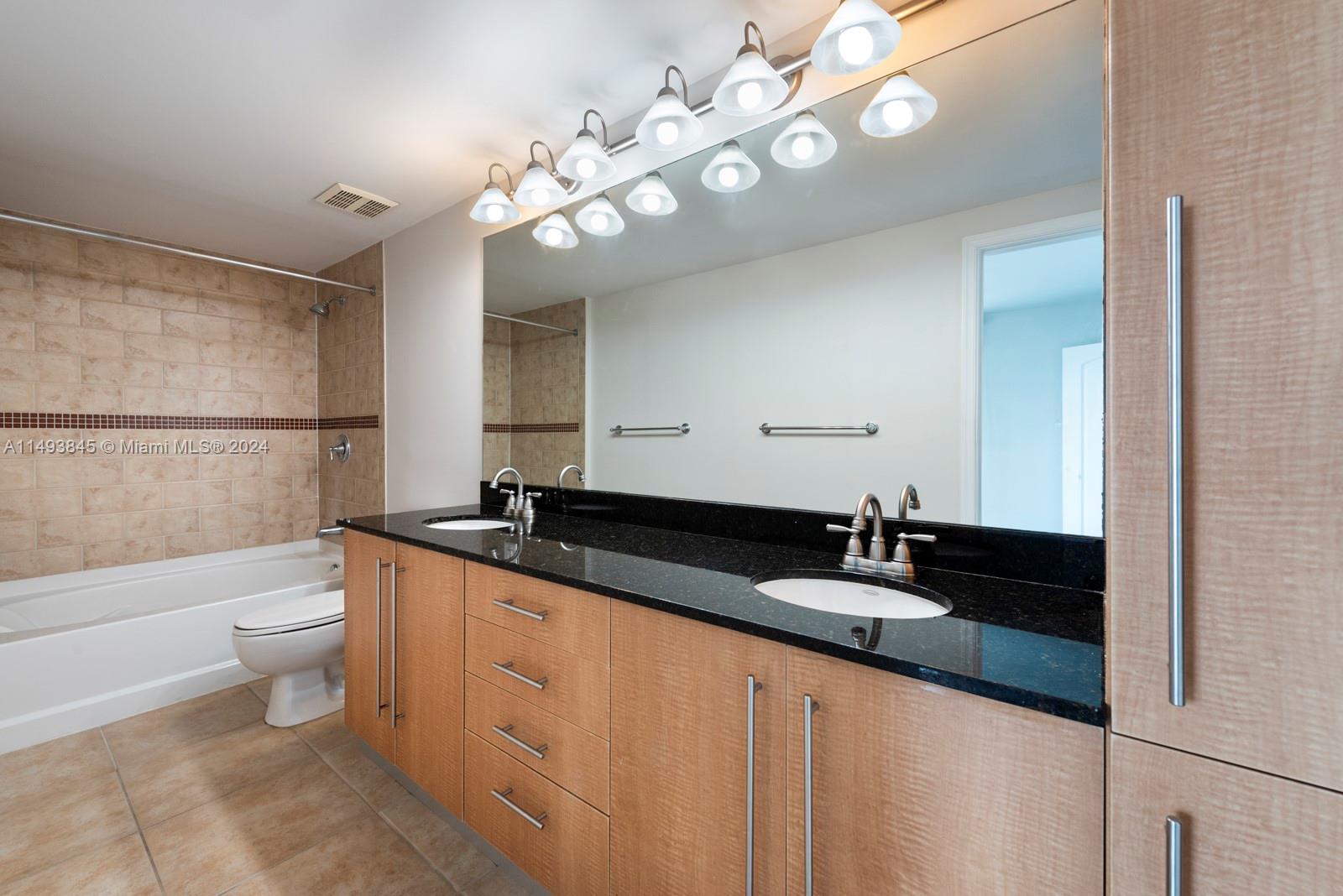 7355 Southwest 89th Street, Unit 510N Miami, FL 33156 - Photo 15 of 52 a bathroom with a granite countertop sink a toilet a mirror and shower