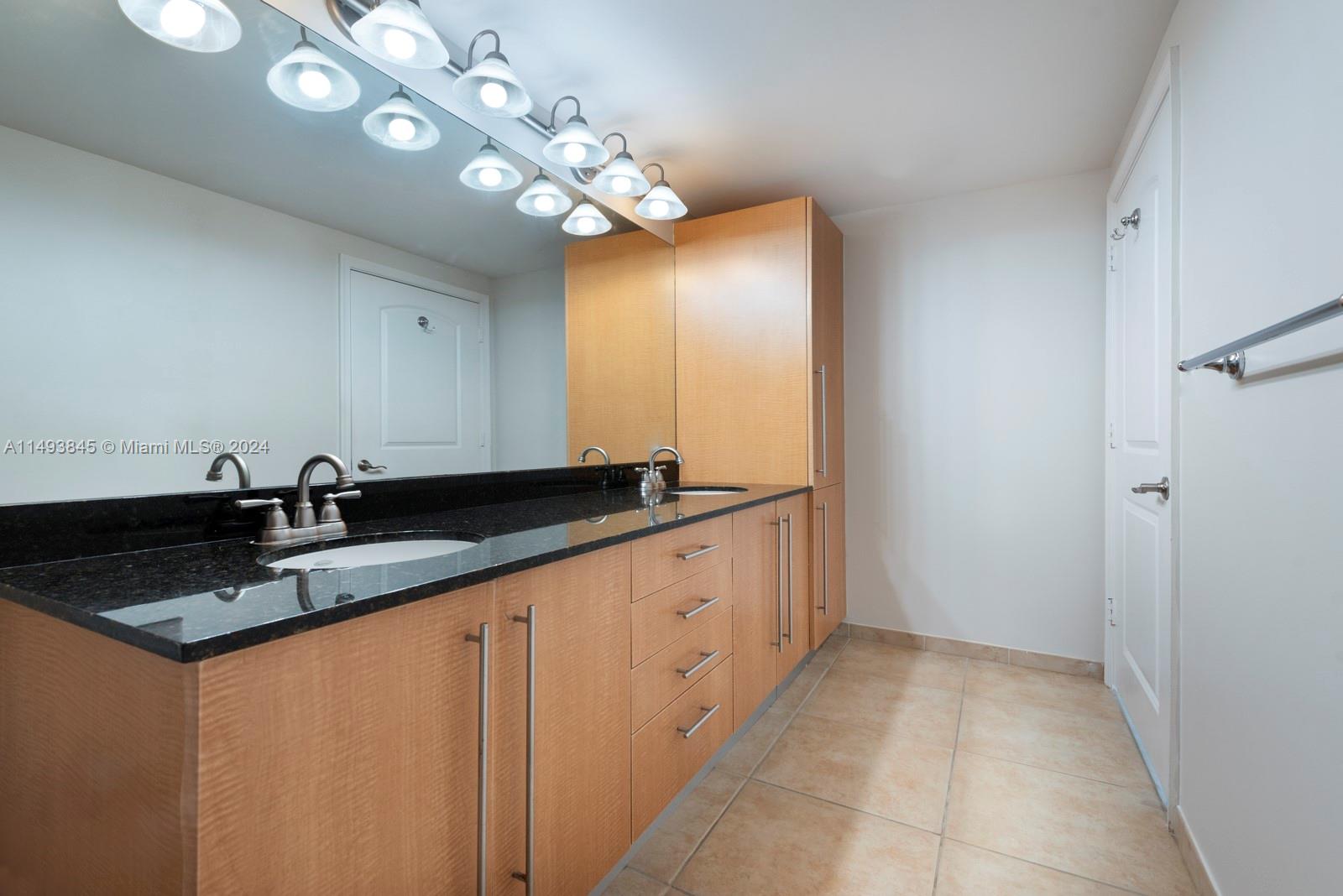 7355 Southwest 89th Street, Unit 510N Miami, FL 33156 - Photo 17 of 52 a bathroom with a granite countertop sink a light fixture and a mirror