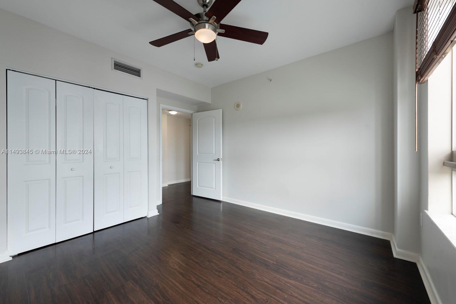 7355 Southwest 89th Street, Unit 510N Miami, FL 33156 - Photo 22 of 52 an empty room with wooden floor chandelier fan and windows