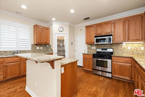a kitchen with stainless steel appliances granite countertop wooden cabinets a stove a sink and a microwave